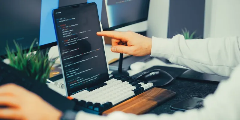 Stock photo: a developer writing code on a laptop and monitor